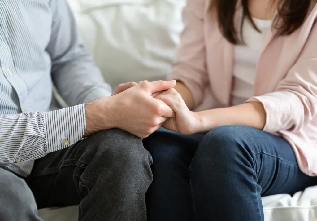 Couple holding hands during a therapy session representing support and relationship healing