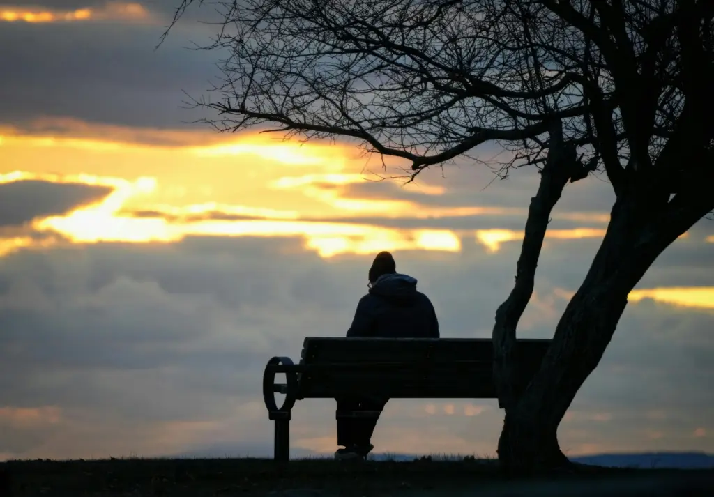 Person sitting quietly in nature reflecting during a season of grief