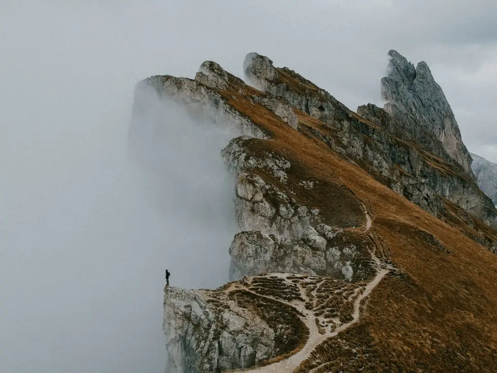 Person standing alone on a foggy cliff edge representing feelings of depression and isolation