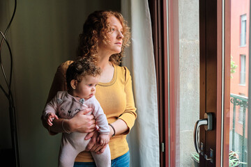 Woman holding her newborn baby looking contemplative