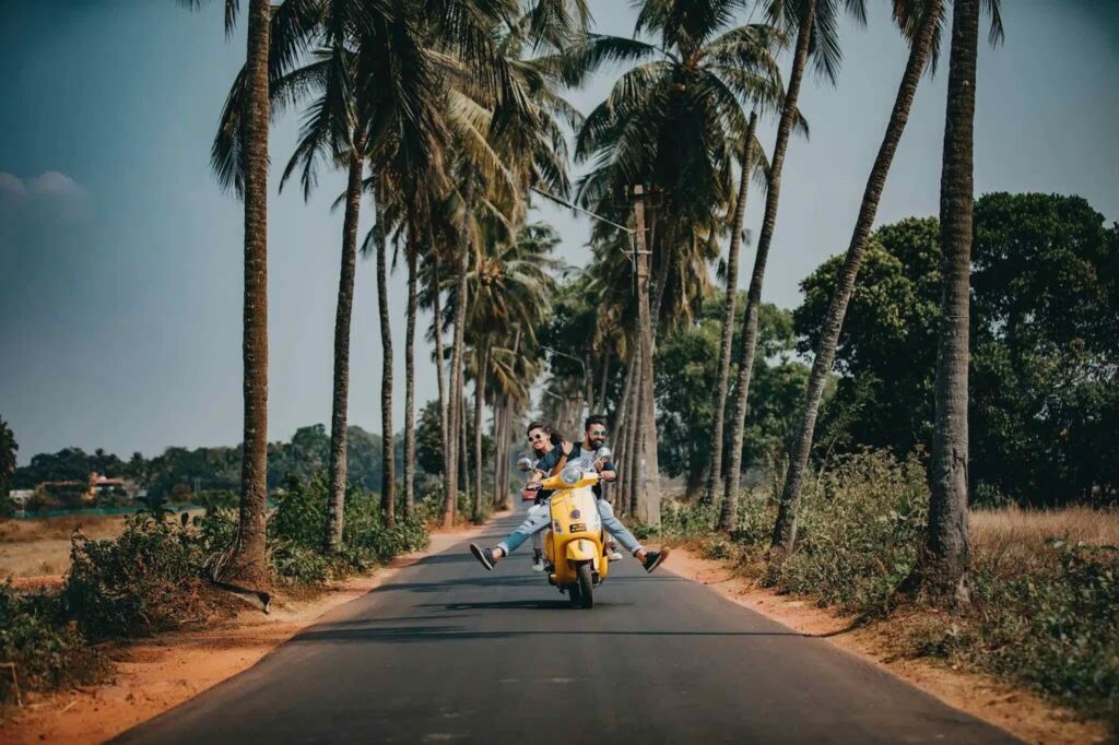 Palm Trees down a lane with 2 people on a scooter.