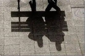 A shadow of 2 people on a bench