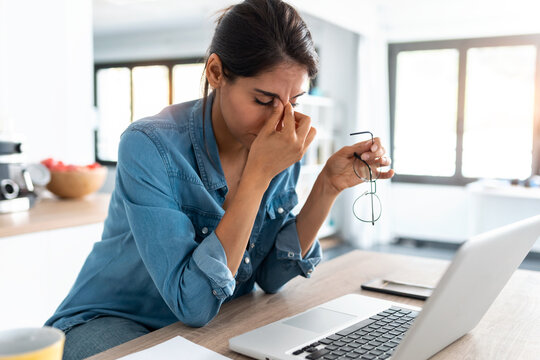 Stressed woman holding glasses at her desk