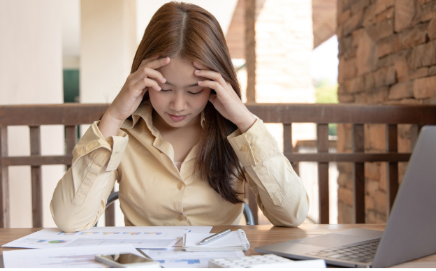 A woman looking in despair at a mess of papers on her kitchen table. 