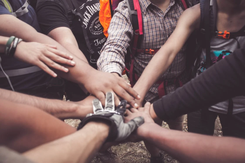 Close up of several friends putting their hands together in a team huddle.