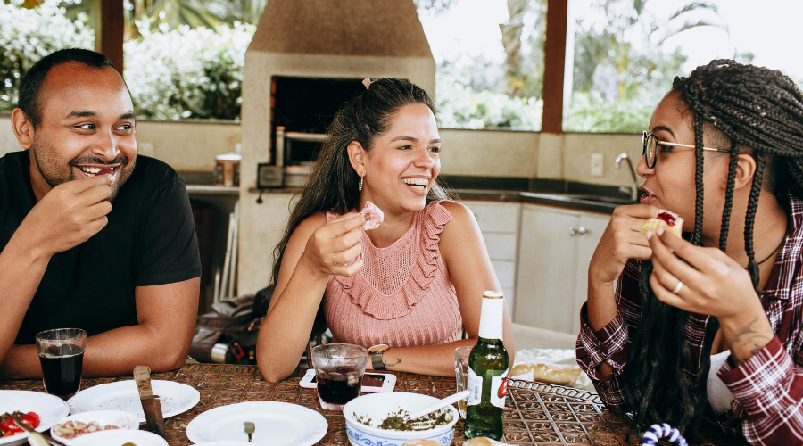 Three friends in a group eating and laughing.