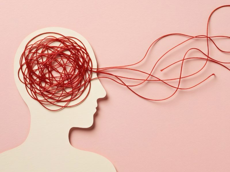 Conceptual illustration of a head silhouette with tangled red lines inside the brain area, representing mental health struggles