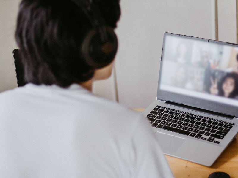 Person Looking towards a computer with a virtual meeting taking place.