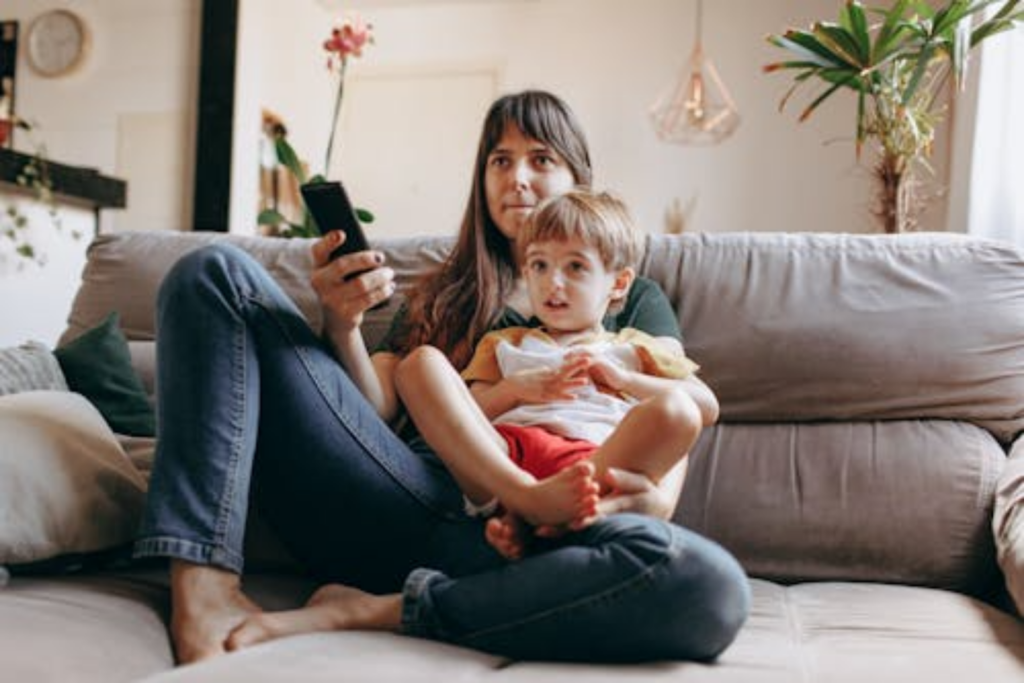 mother sitting on a sofa holding her young child, representing the busy parents who benefit from the flexibility of telecounseling.