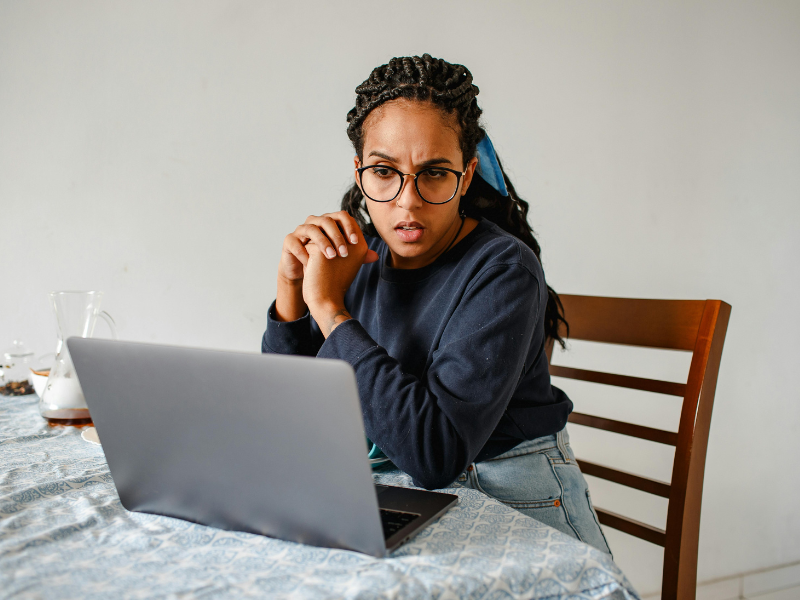 Woman looking towards computer while at a kitchen table.