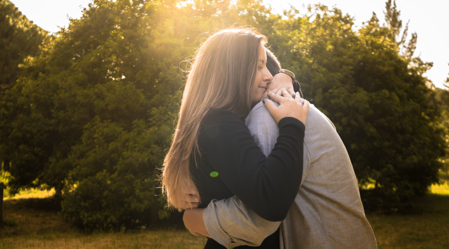 Couple sharing a warm embrace outdoors in golden sunlight, a small romantic gesture that strengthens emotional connection