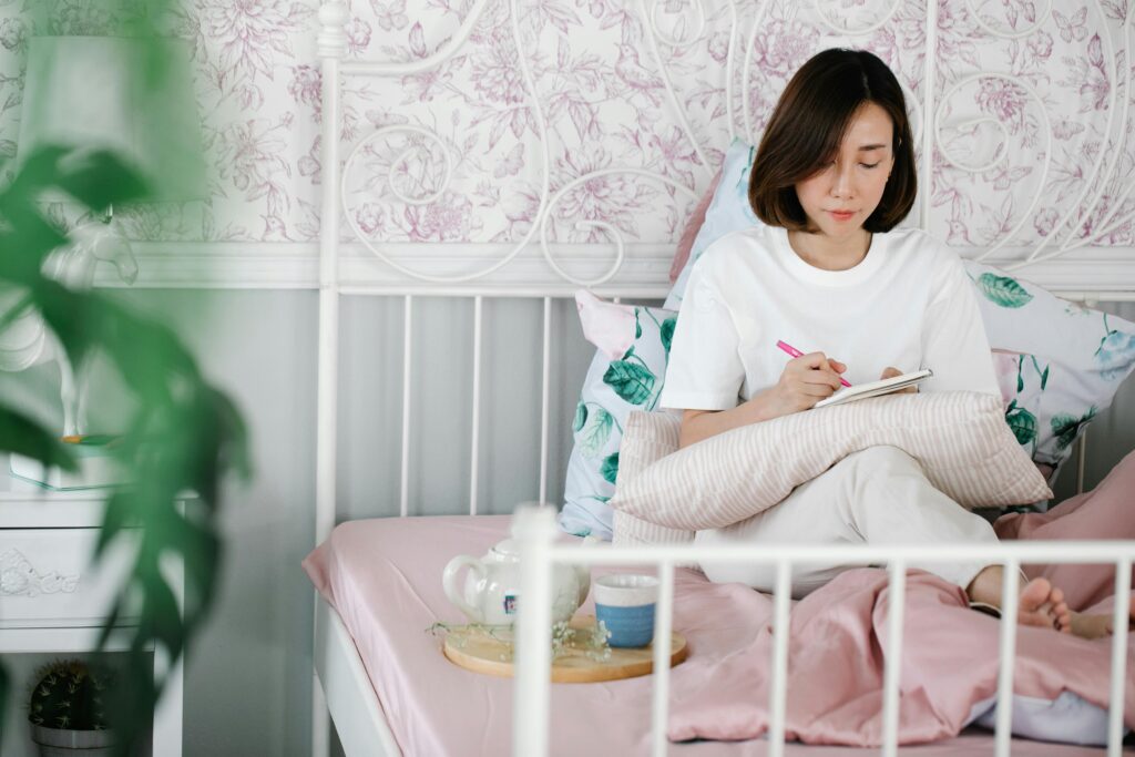 Woman journaling in a calm home setting, representing self-care practices and emotional processing for maternal mental health and postpartum recovery.
