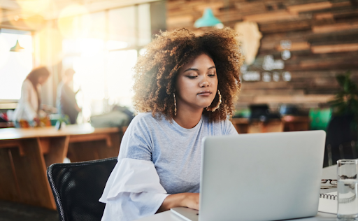 Woman on laptop looking towards her computer in a cafe.