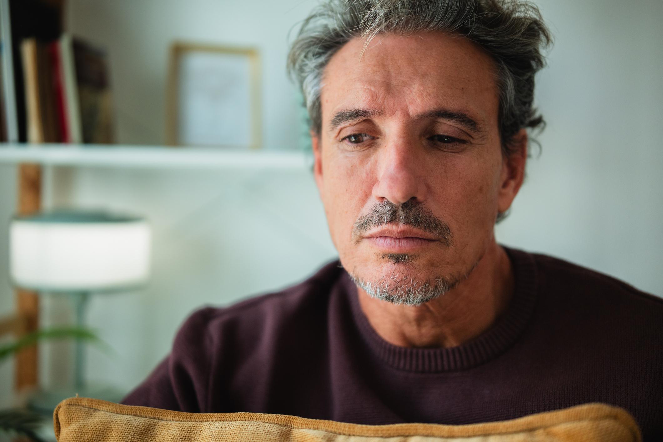 Man sitting quietly indoors with a contemplative expression, reflecting subtle signs of depression in men such as emotional withdrawal and low mood