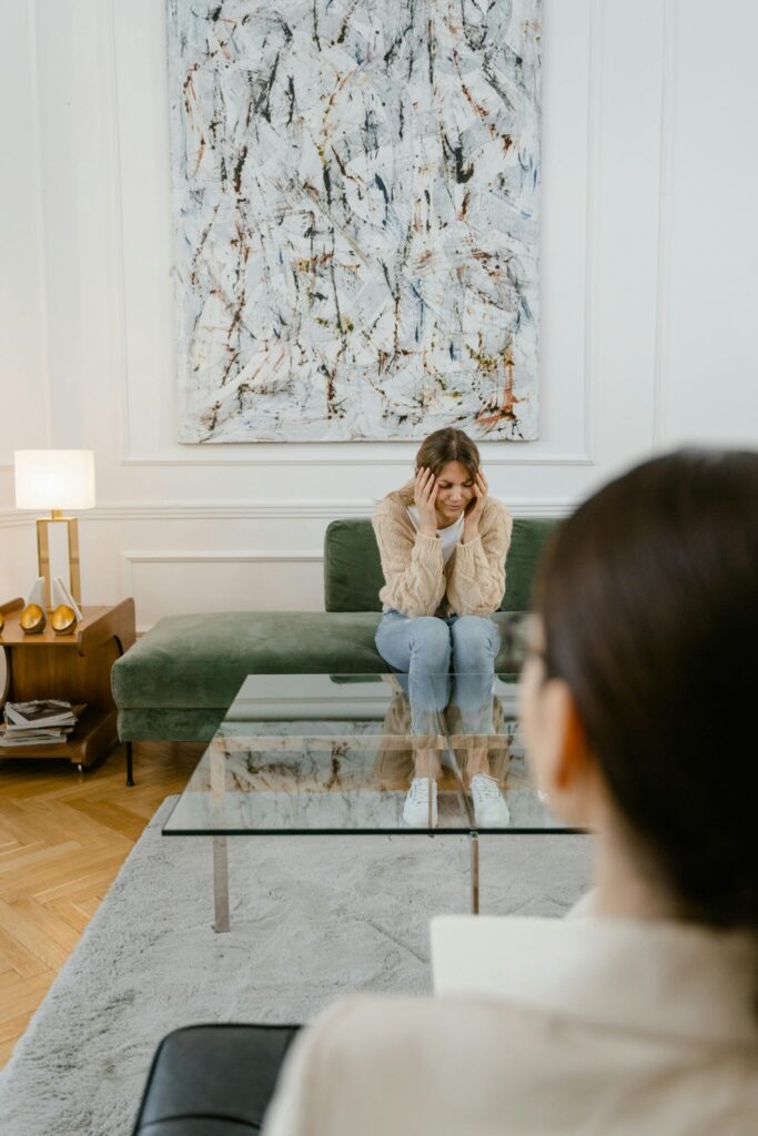 A client sitting on a couch talking with a therapist seated across from them in a counseling office.
