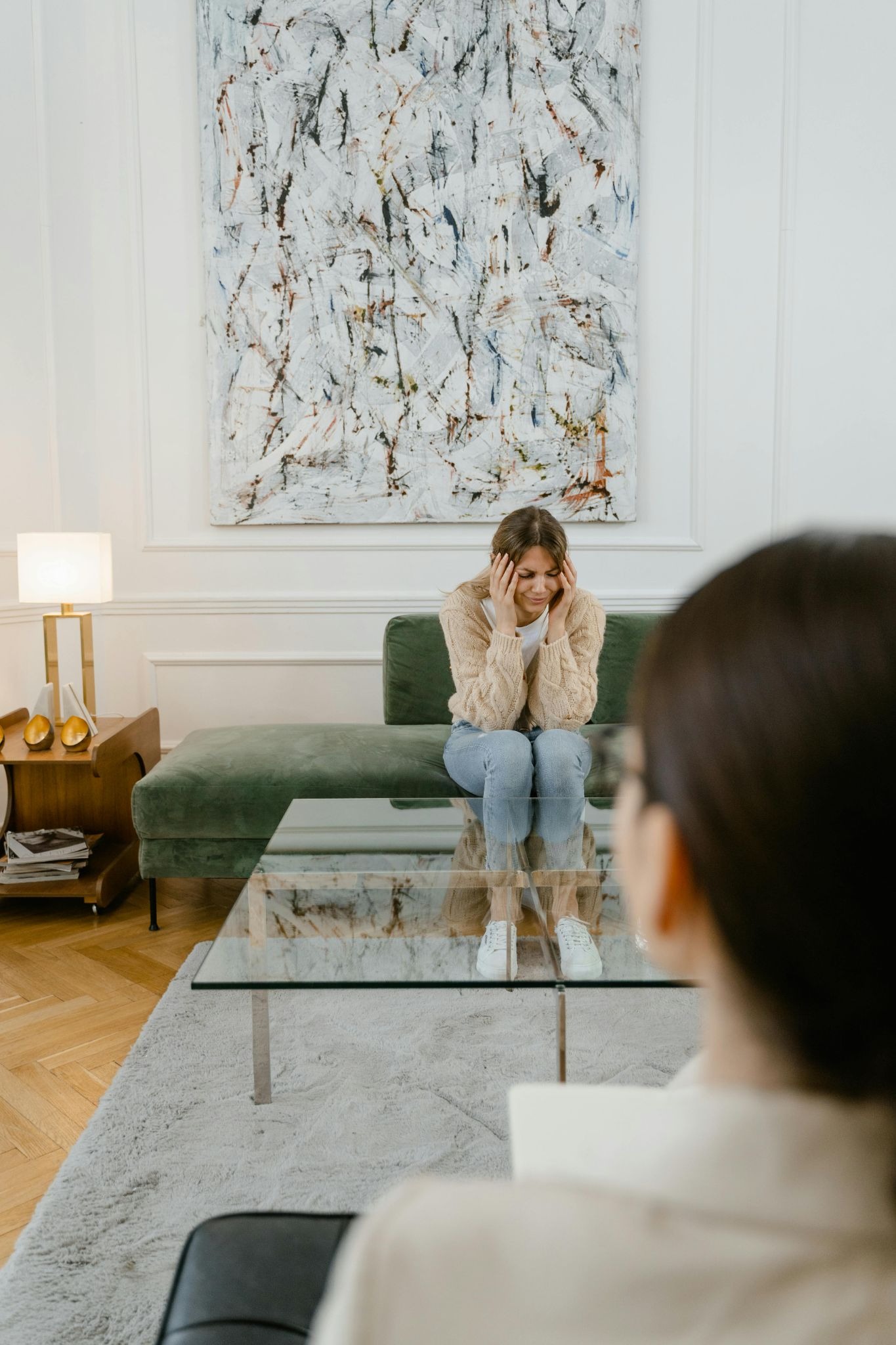 A client sitting on a couch talking with a therapist seated across from them in a counseling office.