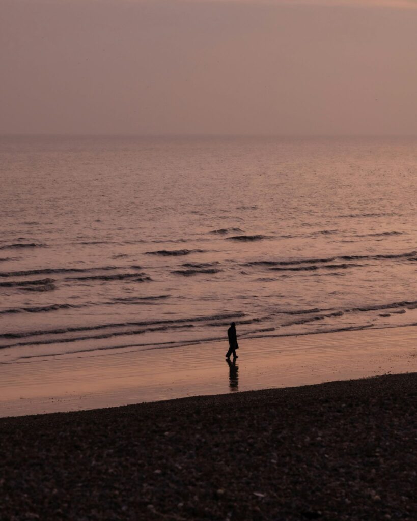 A person coping with summer grief alone near the ocean.