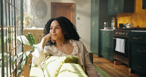A woman looking out the window reflecting on her wellness during a midyear mental health check 