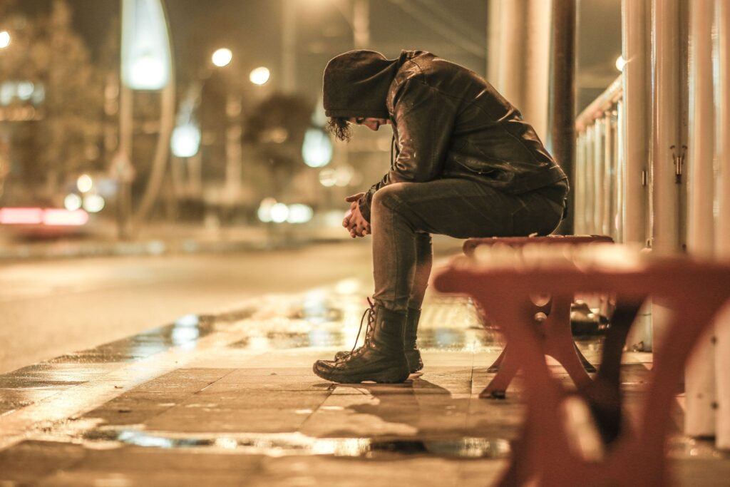Person sitting alone on a bench showing signs that may prompt a suicide prevention conversation