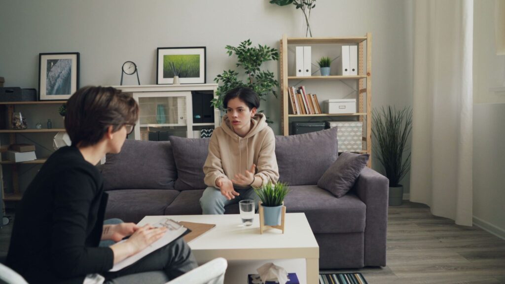 An adolescent engages in open dialogue with a supportive clinician within a contemporary therapeutic space, highlighting the essential role of specialized youth behavioral advocacy.