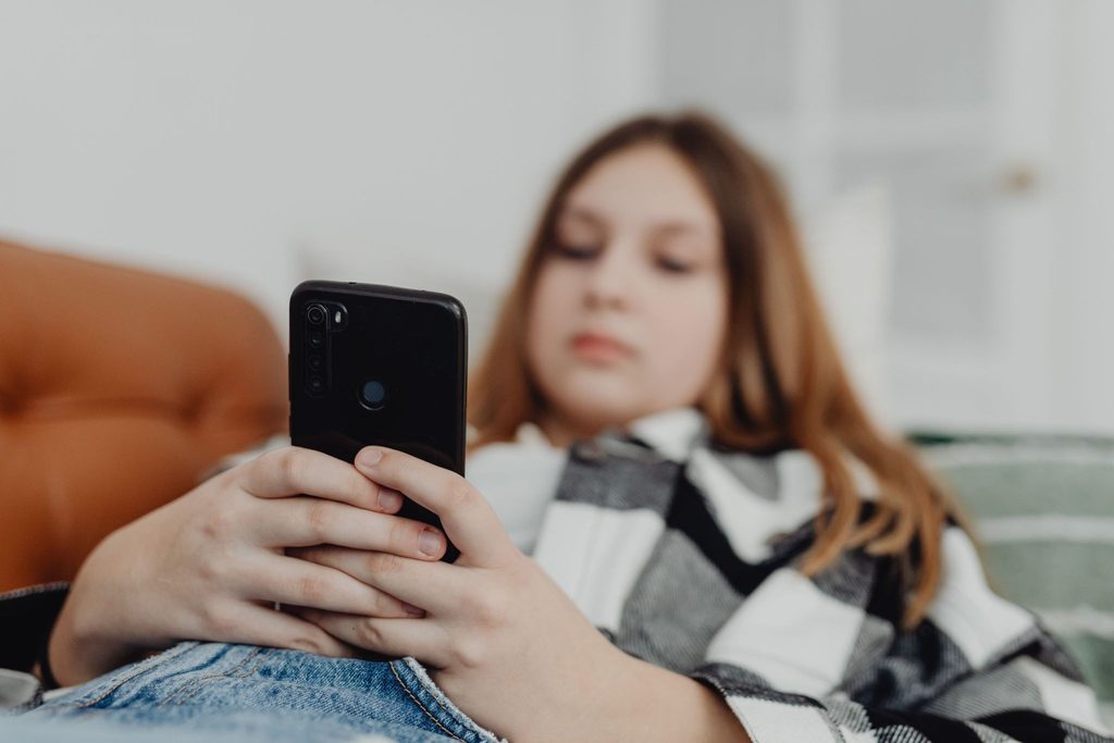 Teen scrolling social media on a phone.